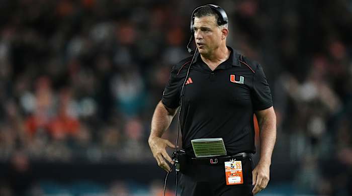 Mario Cristobal walks along the sideline with a hand on his waist